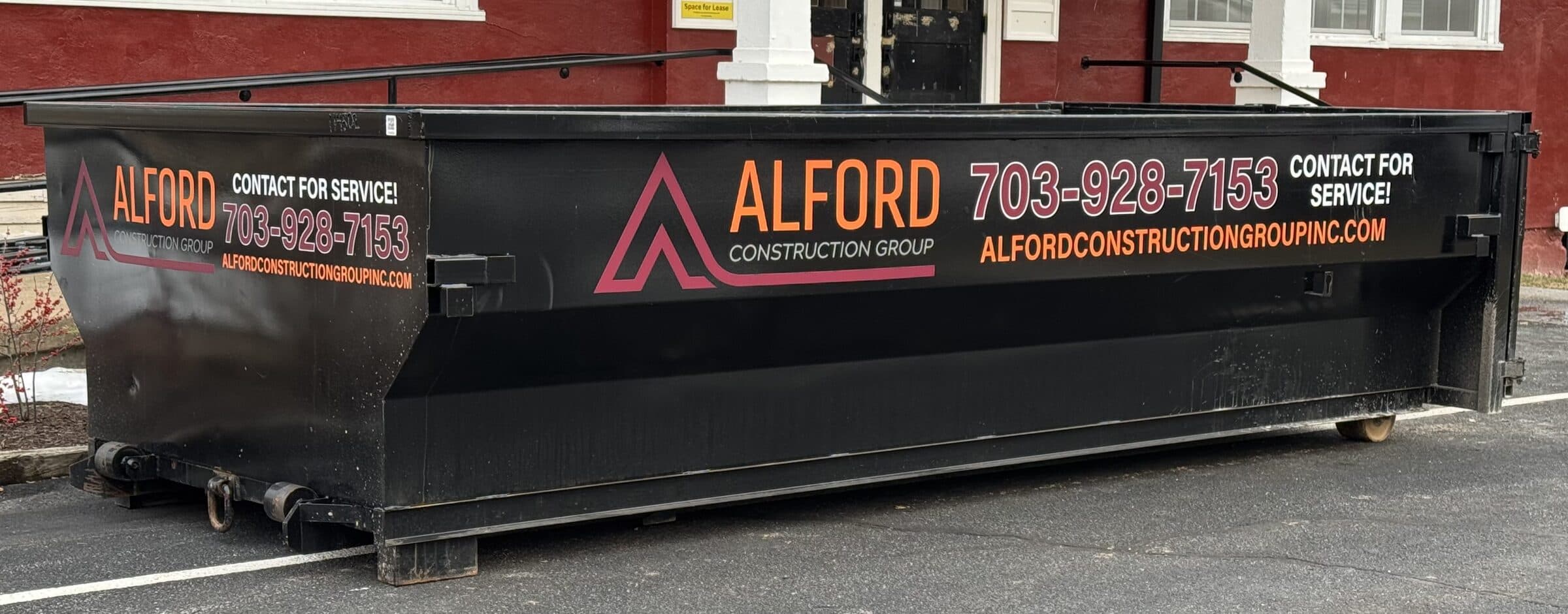 The side of an Alford Construction Group roll-off container, lettered with the company name and phone number