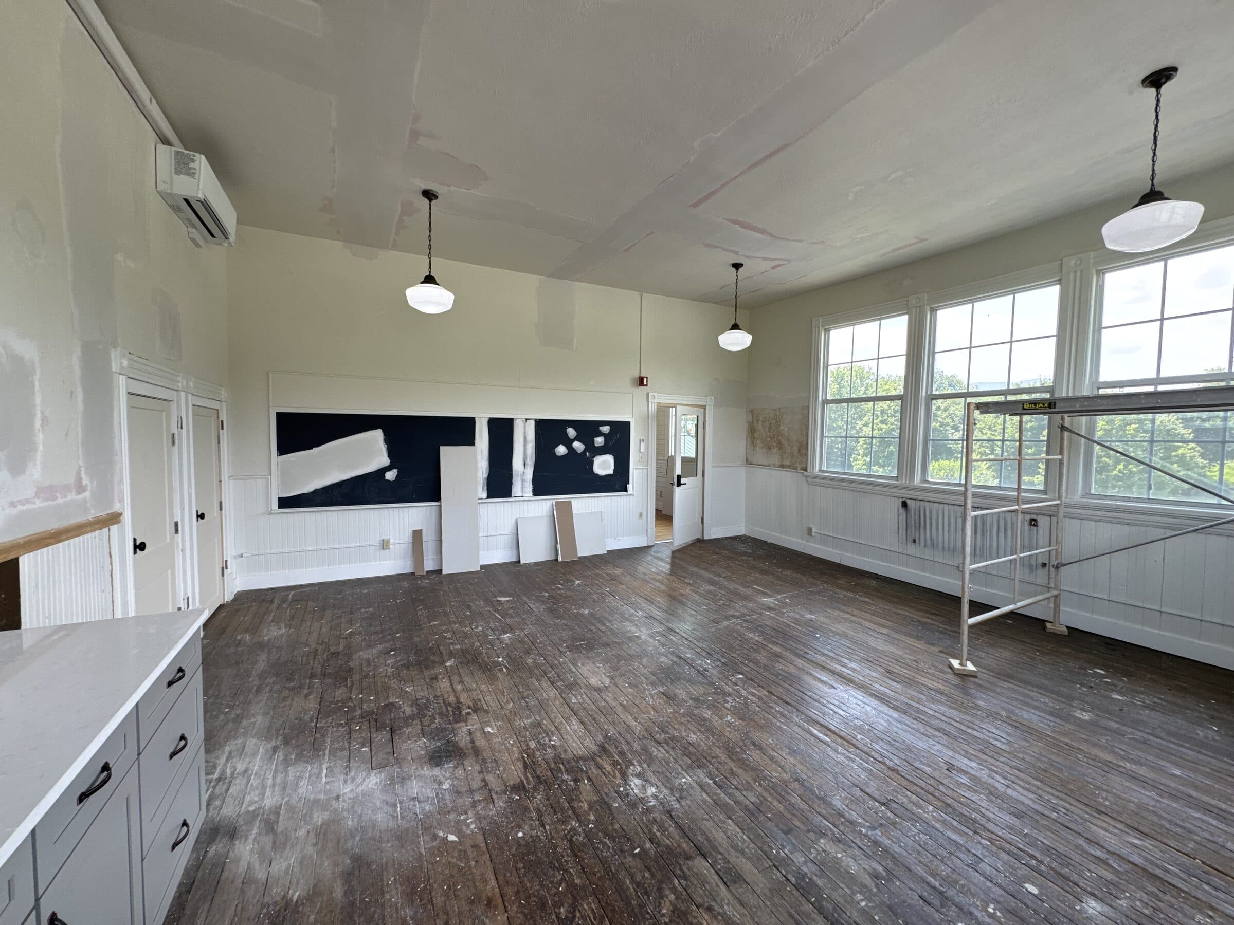 The same classroom from the opposite corner, chalkboards still on the wall and the floor stripped back