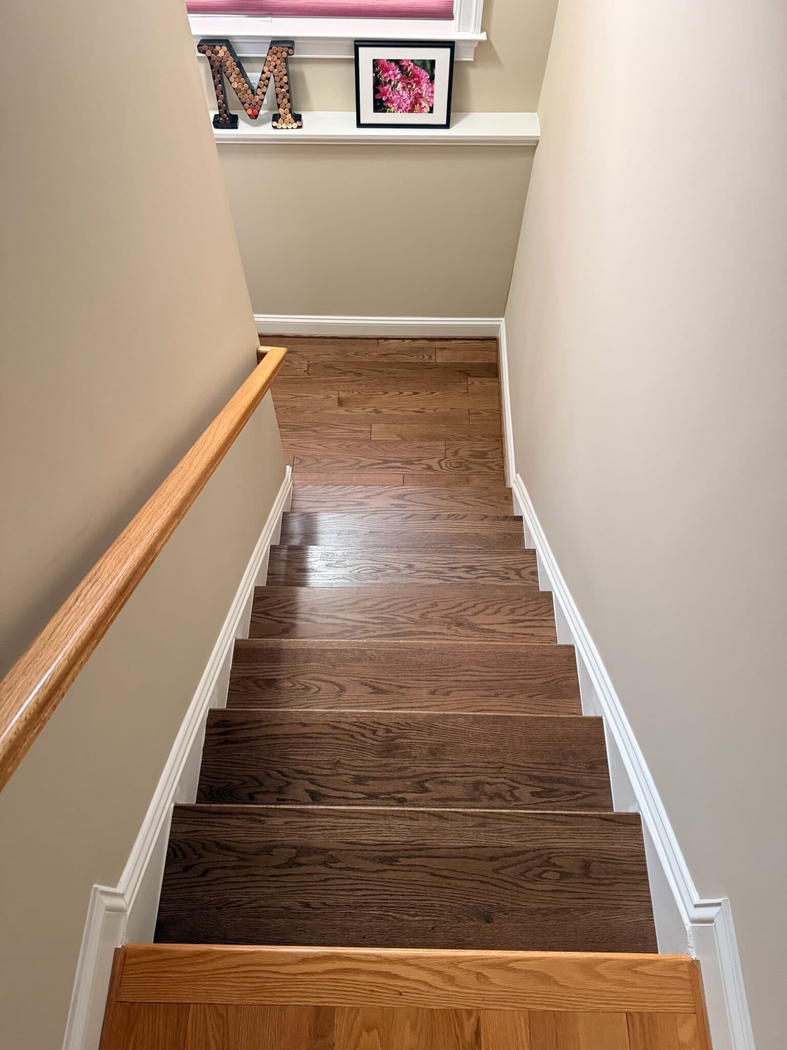 After: the same staircase in stained hardwood, looking down the flight from the same spot