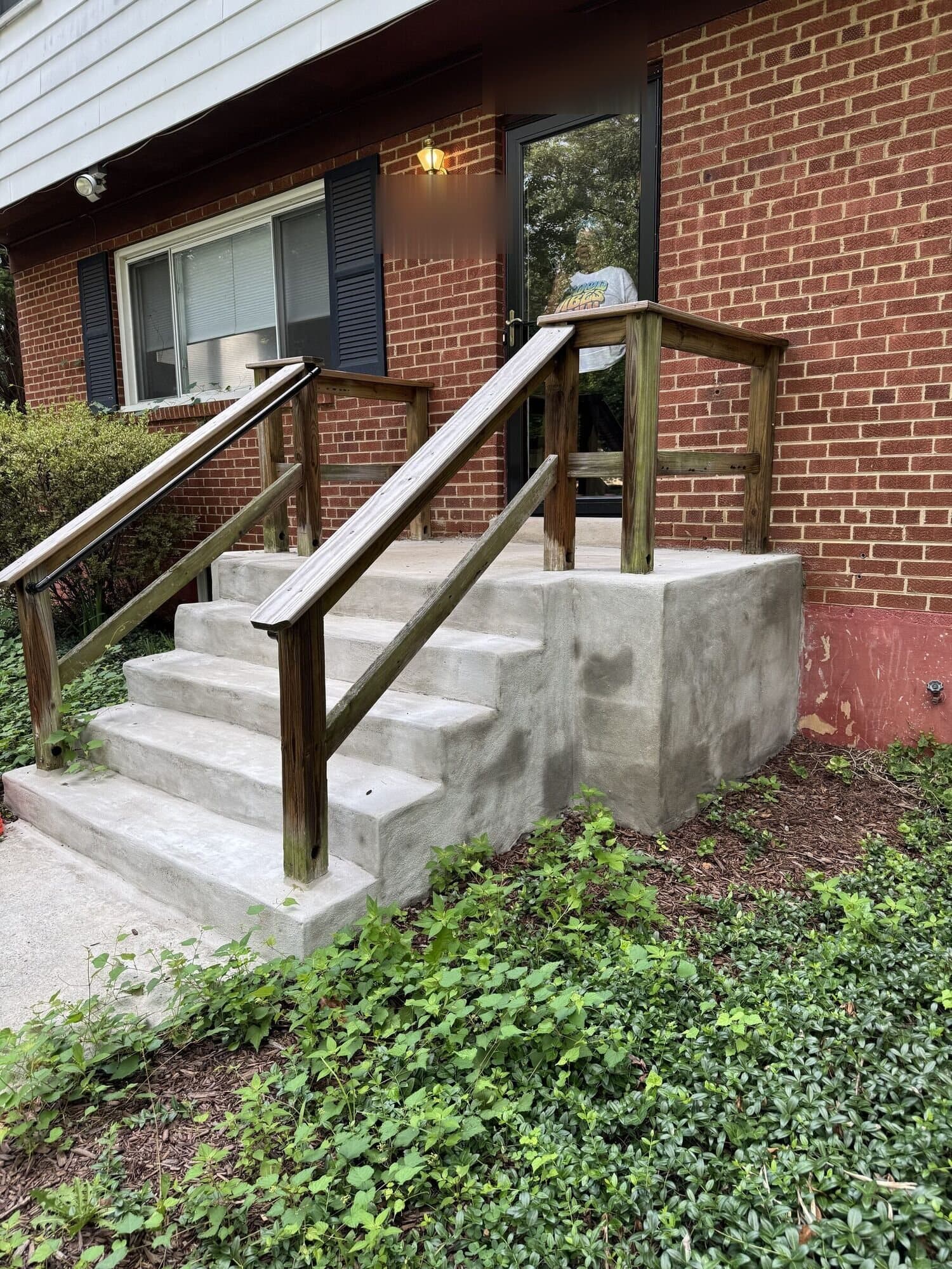 Before: the poured concrete steps and stoop with a plain pressure-treated wood handrail